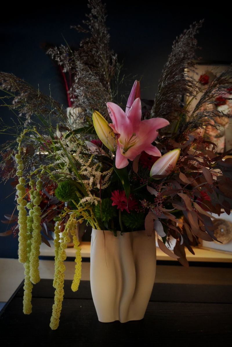 Arrangement mit rosa Lilie, Gräsern und hängendem Amaranthus
