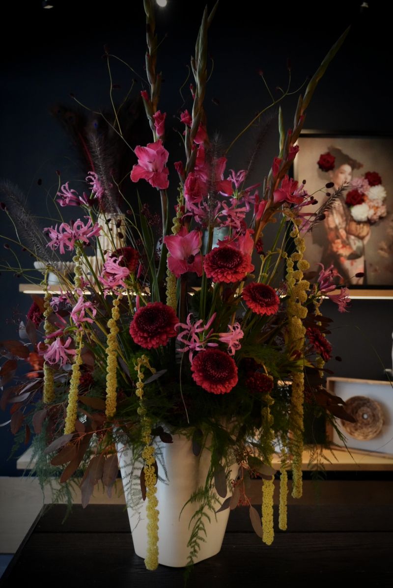 Hohes festliches Arrangement mit pinken Gladiolen, roten Dahlien, Nerinen und hängendem Amaranthus