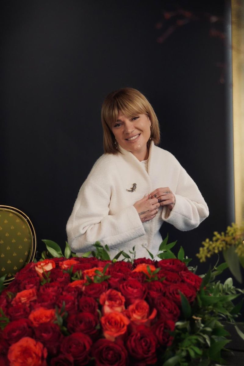 Elmira Kinderknecht lächelt hinter einem großen Herz aus roten Rosen in ihrer Blumengalerie